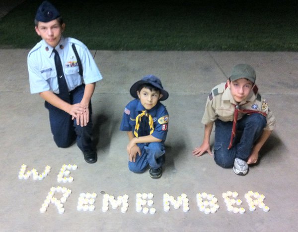 David, Mathew and Andrew Arredondo, all brothers, kneel before a candle lit message “We Remember”