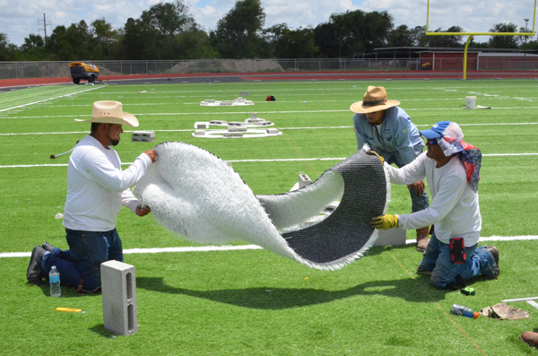 Workers place yard markers on the practice field.