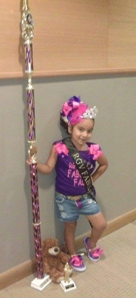 Five year old model Myrykal Nykole Mejia received the Fabulous Faces Queen title and a 5 foot Community Hero Award trophy for collecting over 1,500 school supplies for the Annual Stuff the Bus campaign. 
