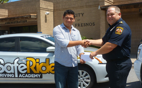 Ricardo Balli of SafeRide Driving Academy hands a sealed envelope of meal certificates from Subway to Los Fresnos Police Chaplain, Dale House, as a token of appreciation for our local police department.